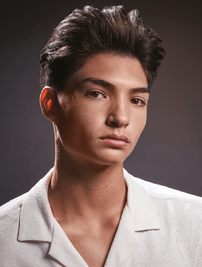Man with a quiff haircut dressed in a white shirt looking at camera