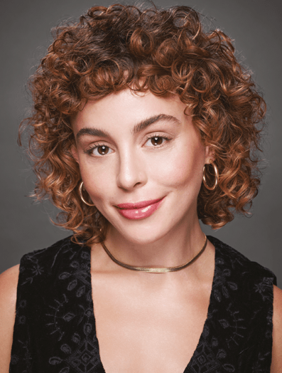 Woman with a shag haircut dressed in a black top looking at the camera