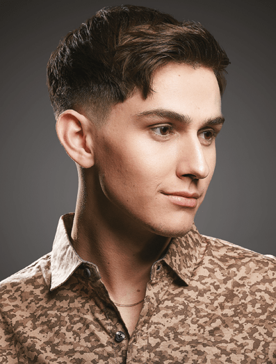 Man with a textured fade haircut dressed in tan shirt looking off to the right