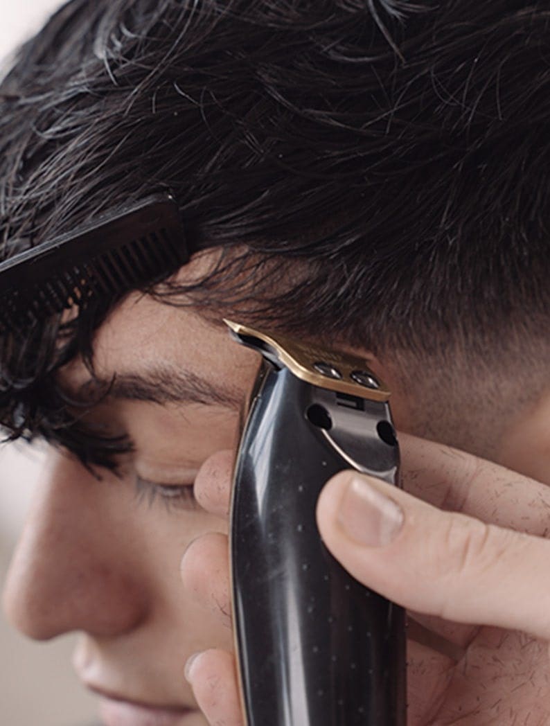 Barber using Wahl Gold Detailer Li to cut lines into a model's hair
