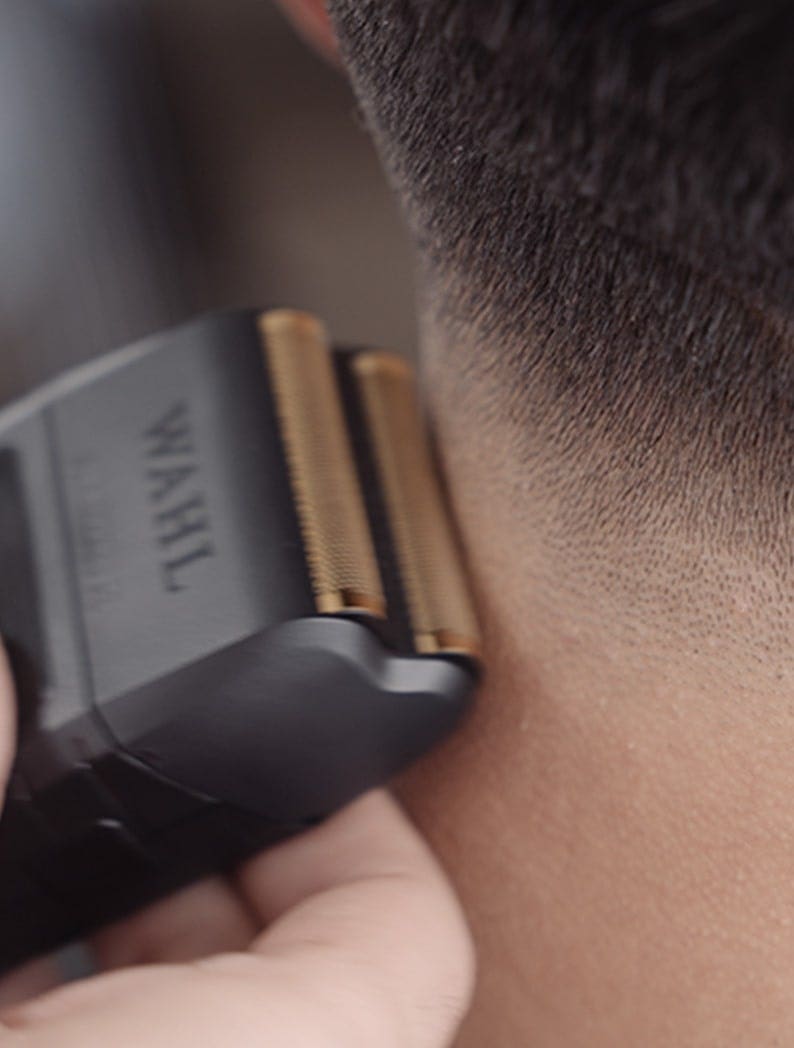Barber using a Wahl Vanish shaver to finish model's neckline.