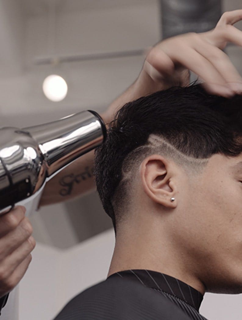 Barber using Wahl Barber Dryer to style model's hair.