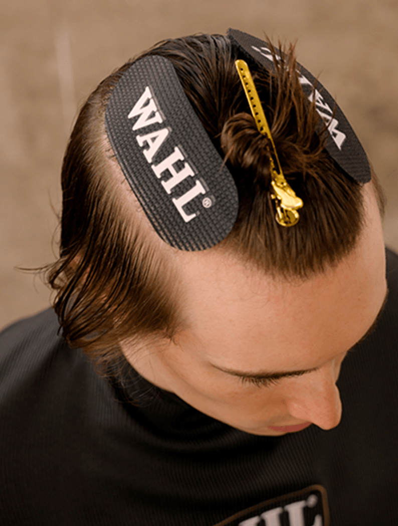 Dark-haired model with hair held in clips wearing a barber cape.