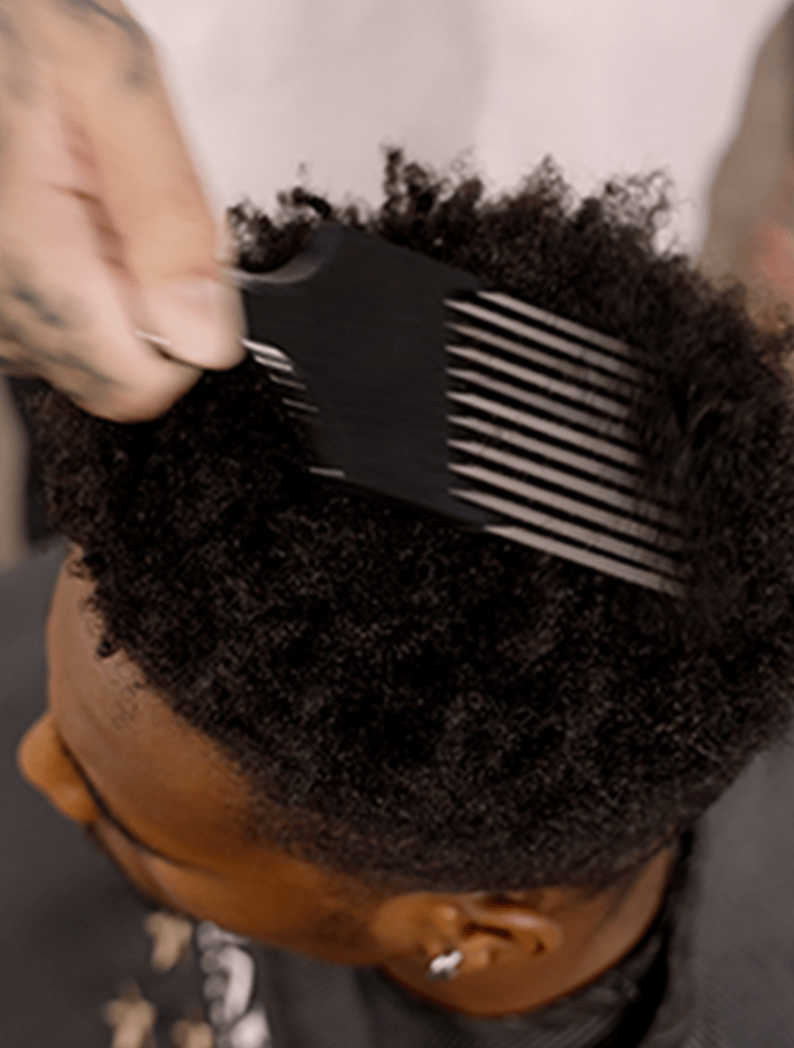 Barber using pick comb to tease out hair