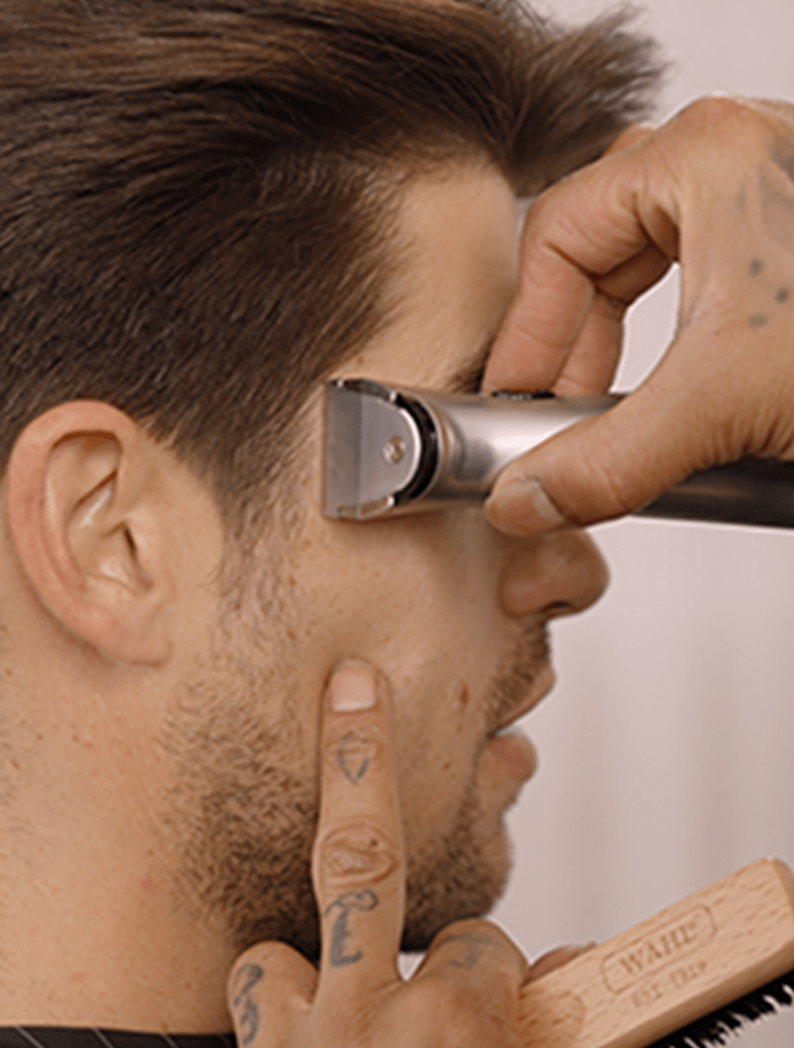 Barber using Wahl Beret trimmer to trim model's sideburns