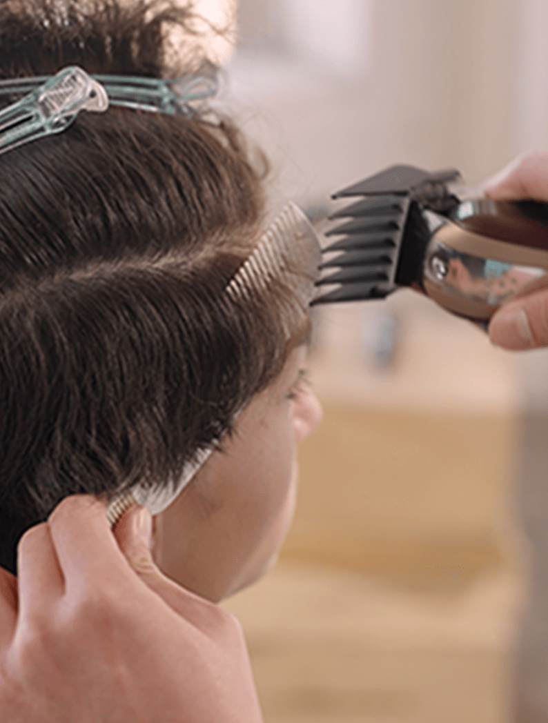 Barber using Wahl Cordless Legend clipper to cut hair around clips in model's hair