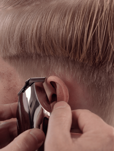 Barber using a Wahl Detailer Li trimmer to shape hair around model's ear.